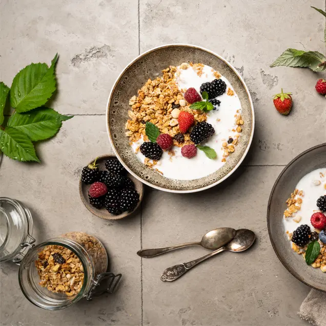 Zwei Schüsseln Joghurt mit Müsli auf dem Tisch.