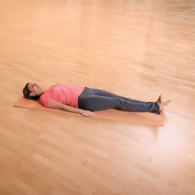 Frau liegt auf dem Rücken auf einer Yogamatte und hebt ein Bein leicht an.