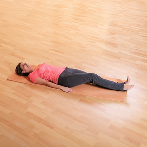 Frau liegt auf dem Rücken auf einer Yogamatte und hebt ein Bein leicht an.