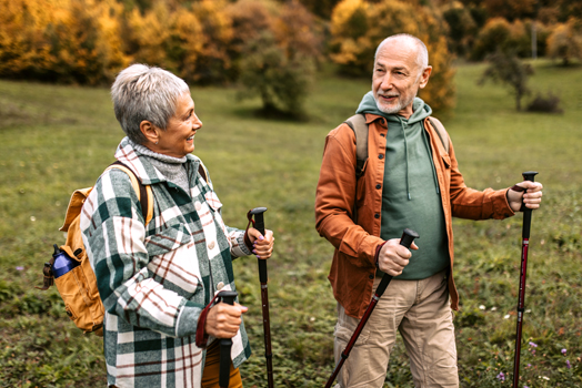 Älteres Paar beim Wandern mit Nordic Walking-Stöcken.